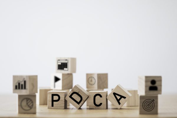 Imagem de vários pequenos cubos de madeira. No meio da imagem há quatro cubos, simbolizando o ciclo PDCA.